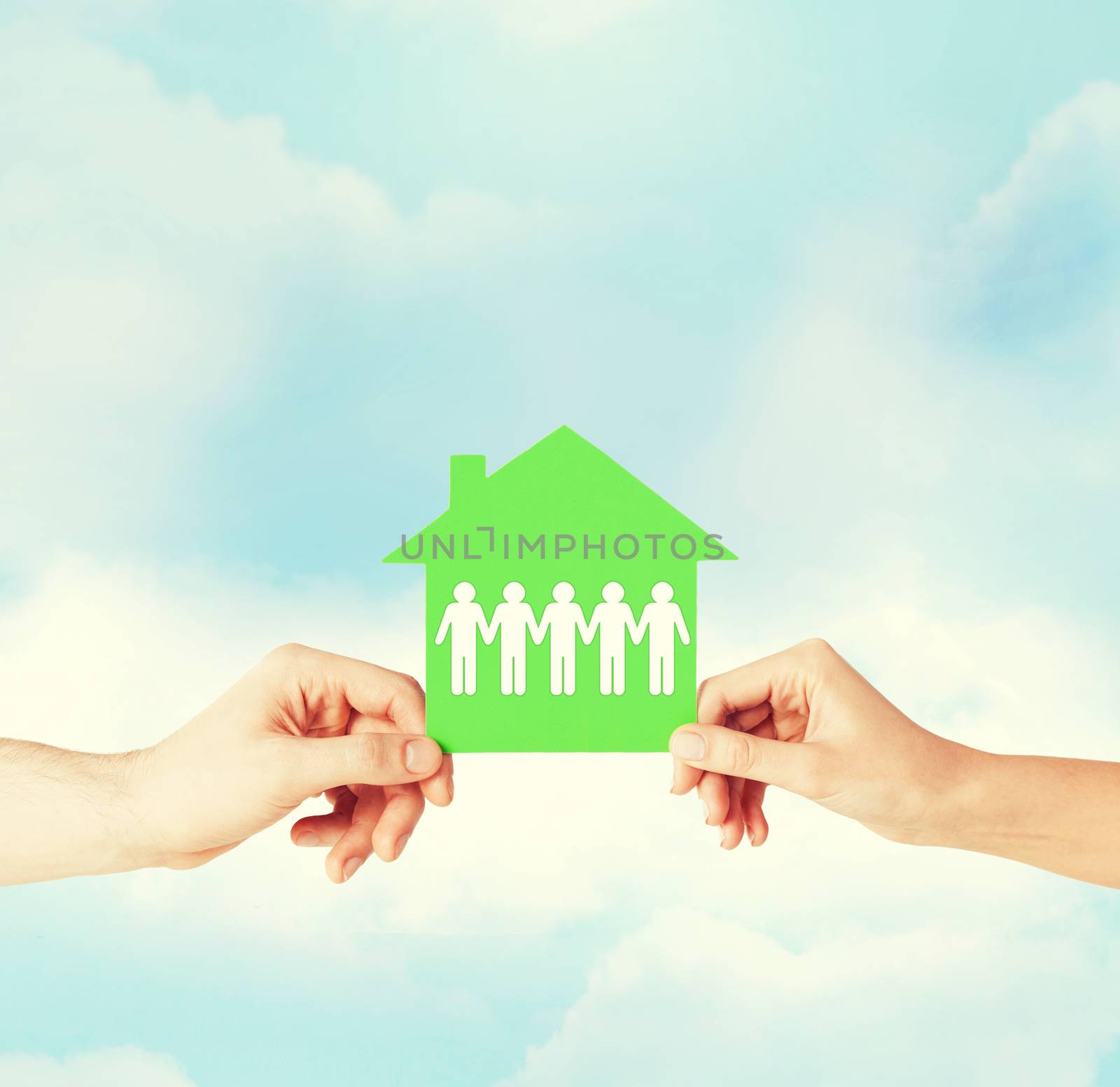 real estate and family home concept - isolated closeup picture of male and female hands holding green paper house