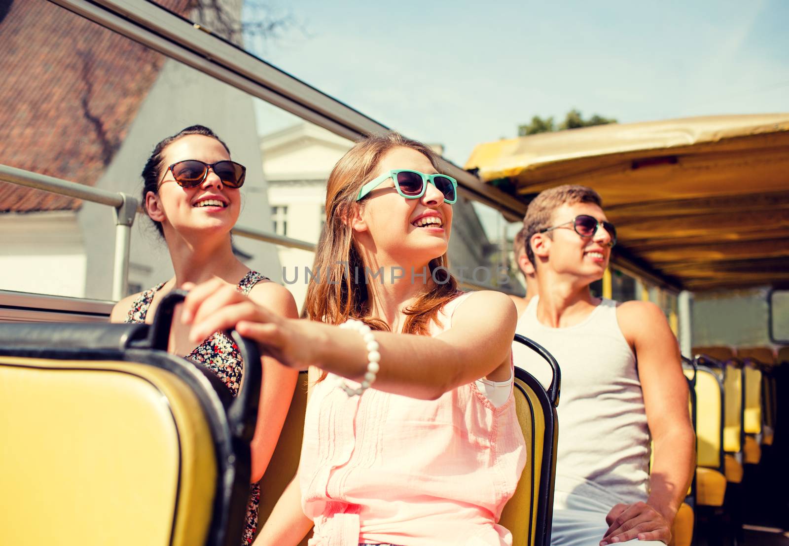 friendship, travel, vacation, summer and people concept - group of smiling friends traveling by tour bus