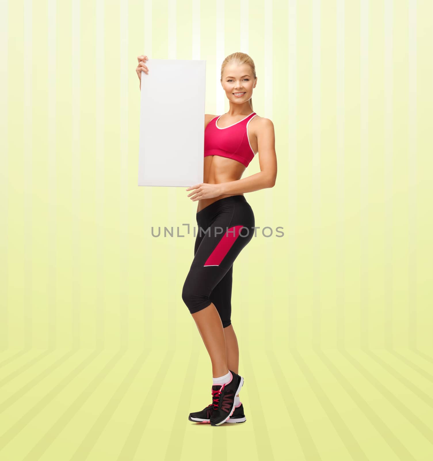 sport, fitness, people and advertisement concept - happy smiling sportswoman with white blank board over yellow striped background
