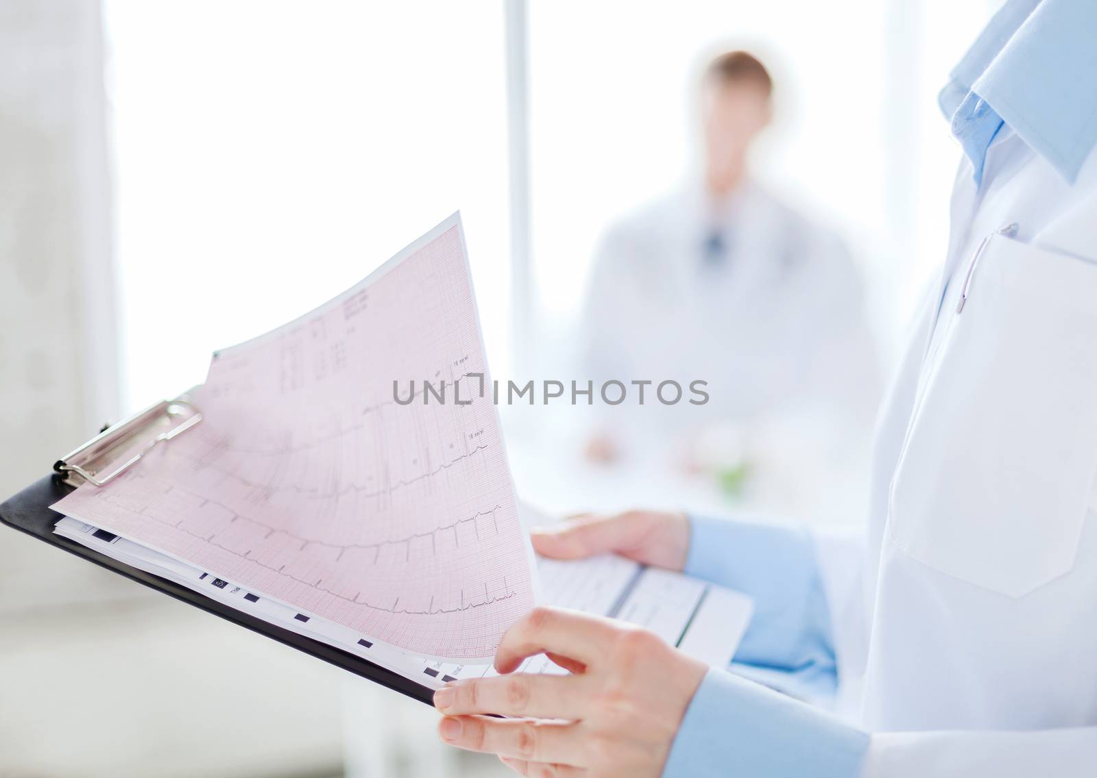 healthcare and medicine concept - close up of female holding clipboard with cardiogram