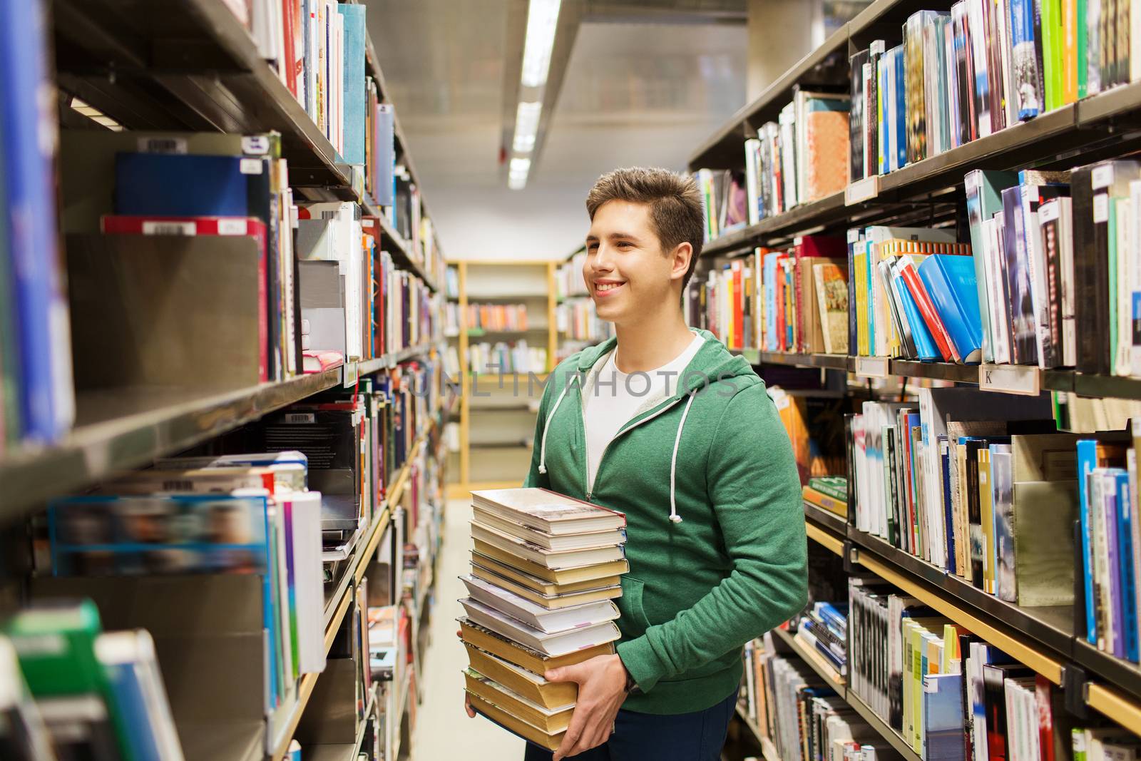 people, knowledge, education, literature and school concept - happy student or young man with book in library