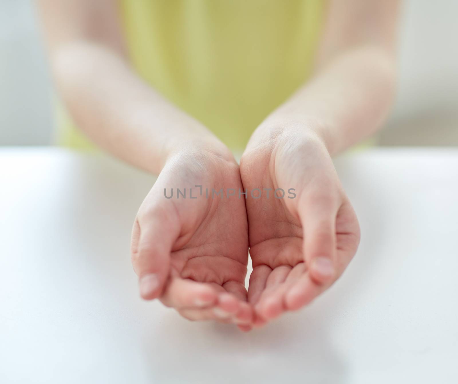 people, charity, childhood and advertisement concept - close up of child cupped hands at home