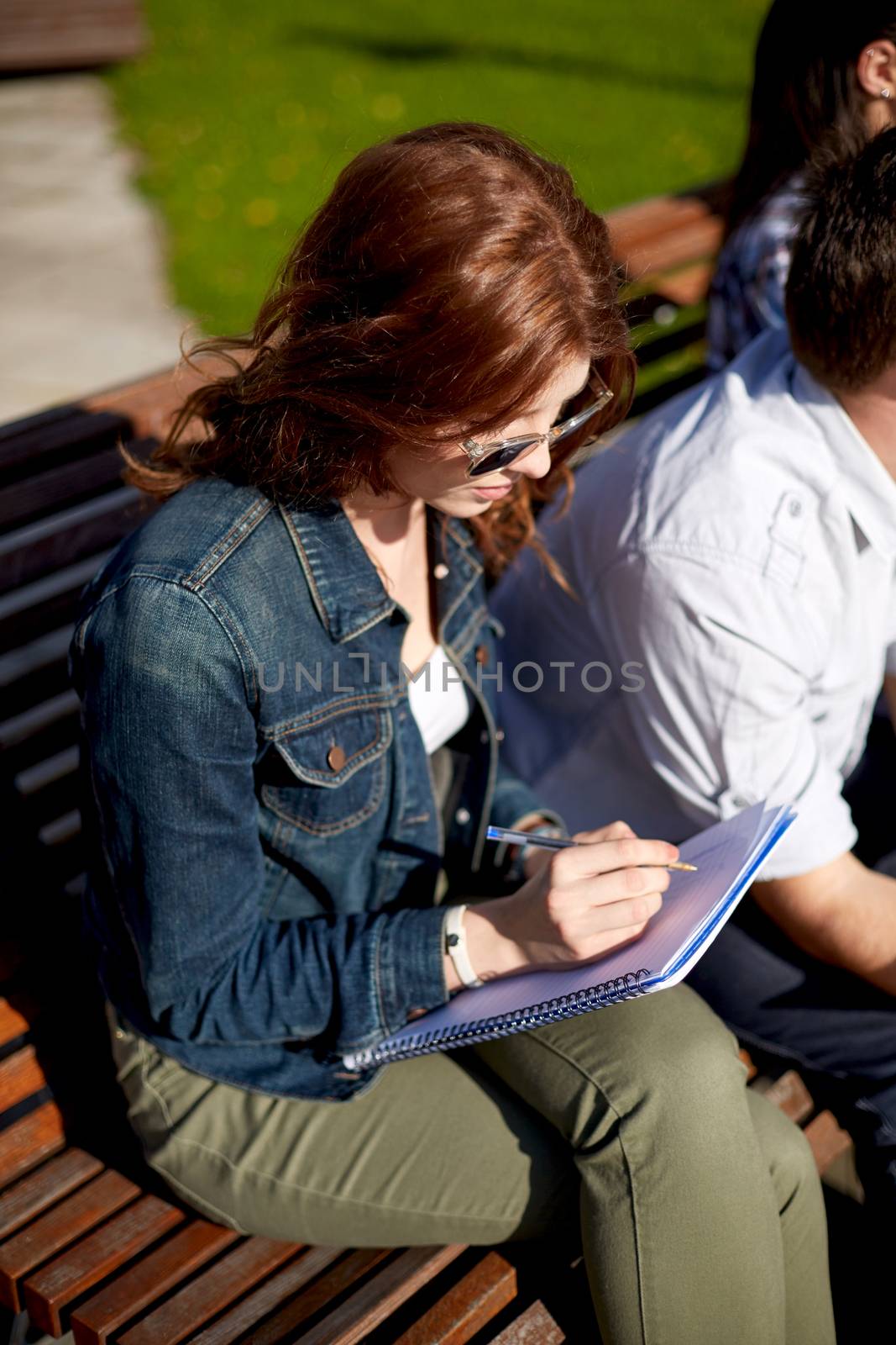 summer, education, learning and teenage concept - student girl writing to notebook at campus