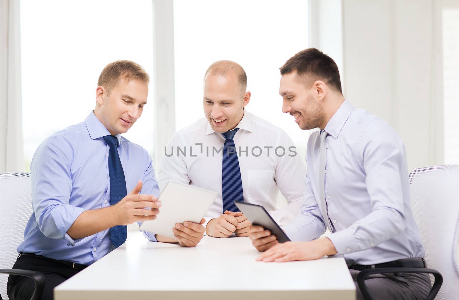 three smiling businessmen with tablet pc in office by dolgachov
