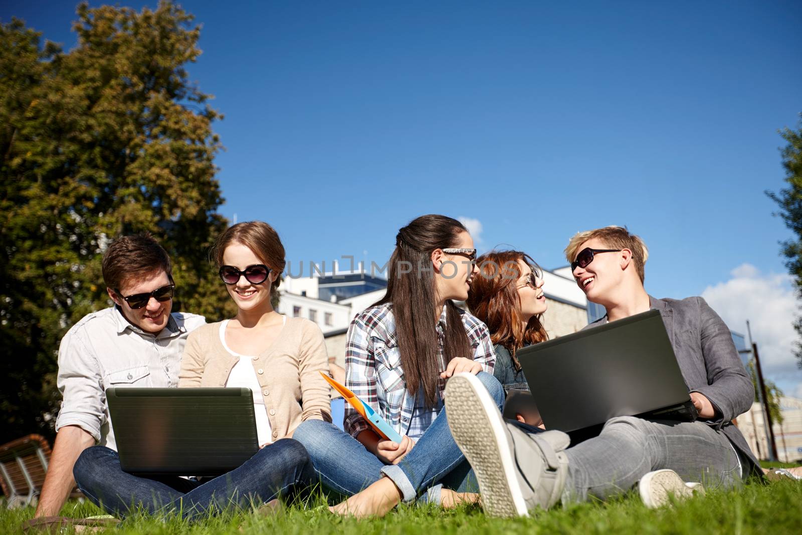 summer, communication, technology , education and teenage concept - group of students or teenagers with laptop computers at park or campus