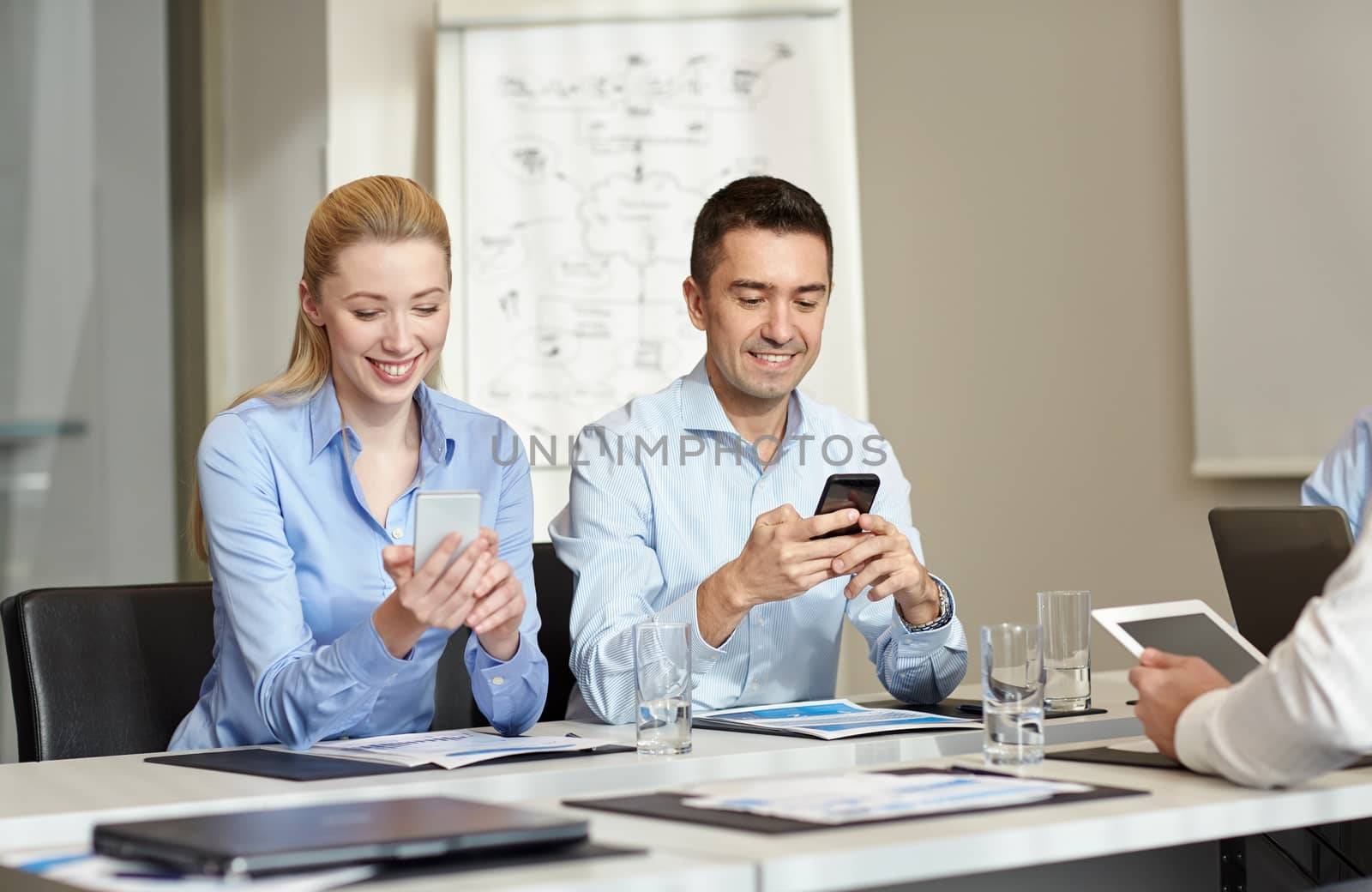 business, people and technology concept - smiling business team with smartphones meeting in office