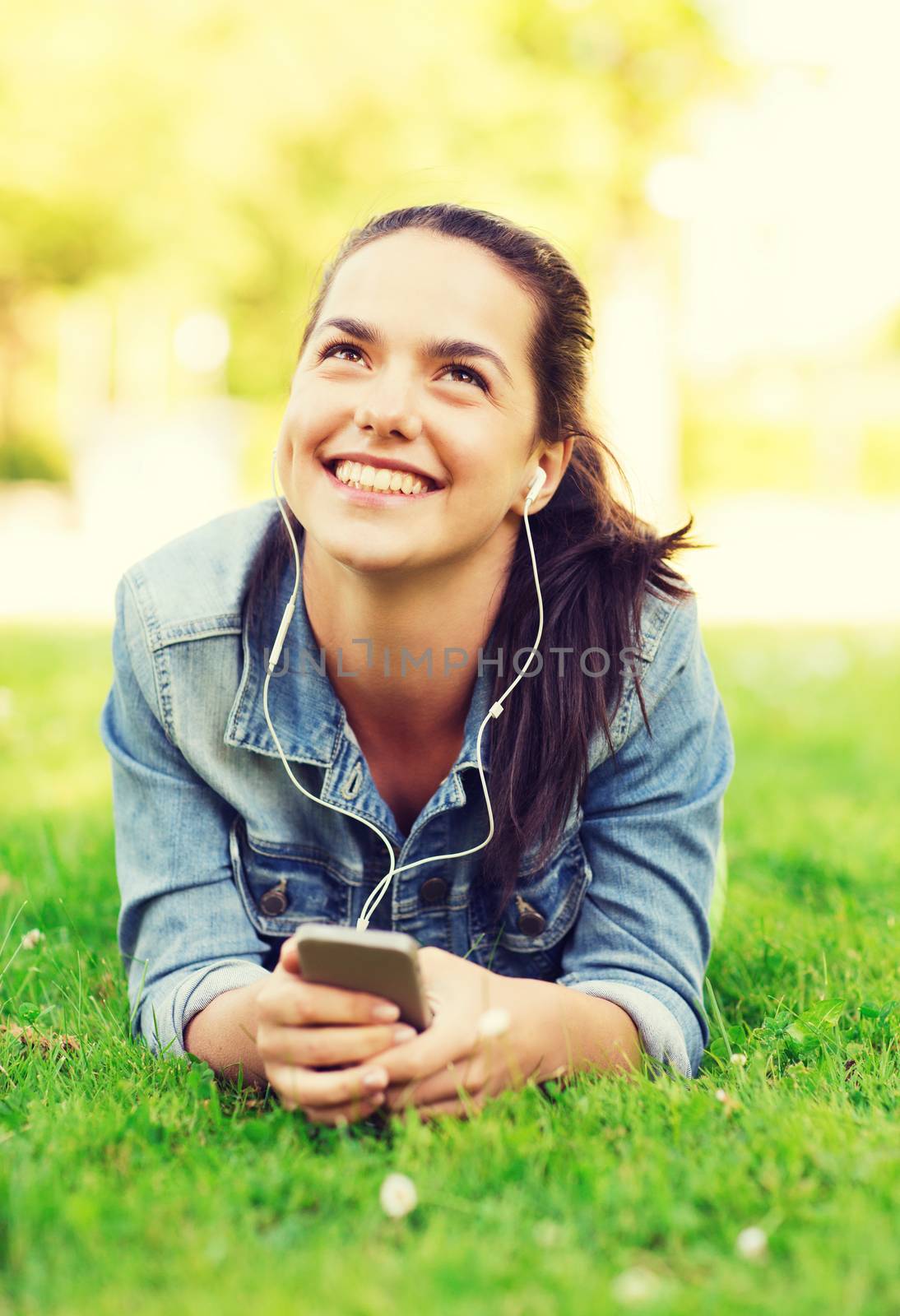 smiling young girl with smartphone and earphones by dolgachov