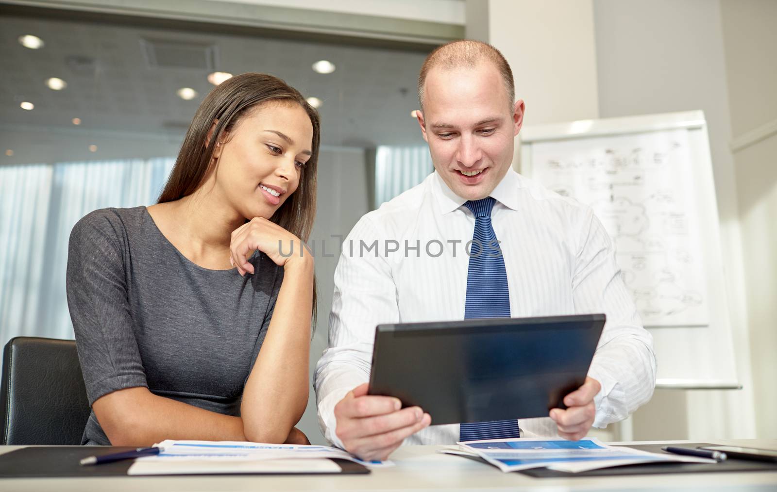 smiling businesspeople with tablet pc in office by dolgachov