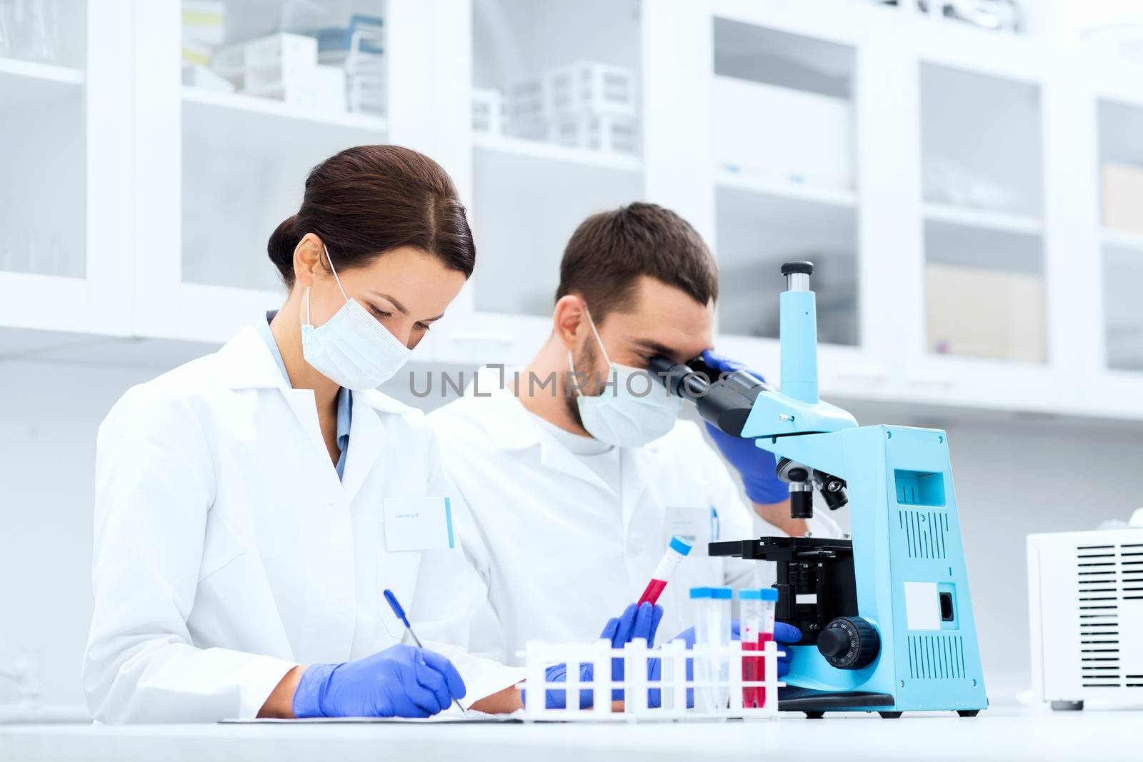 scientists with clipboard and microscope in lab by dolgachov