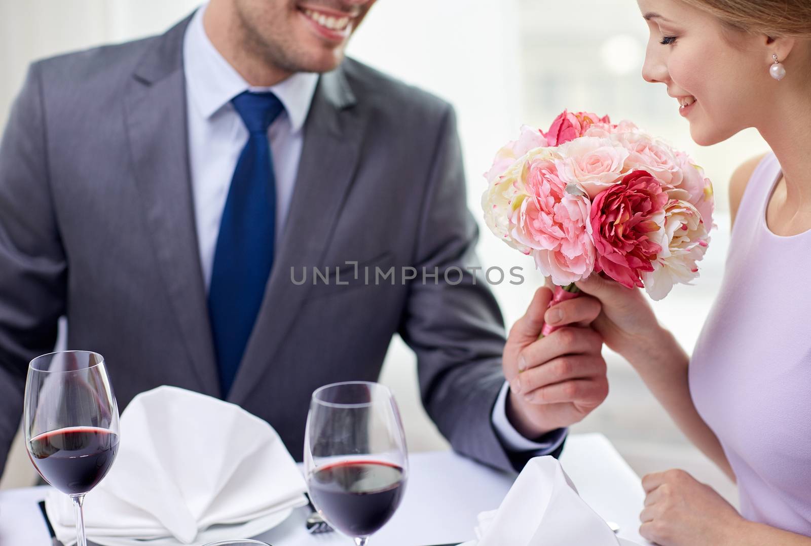 young couple with glasses of wine at restaurant by dolgachov