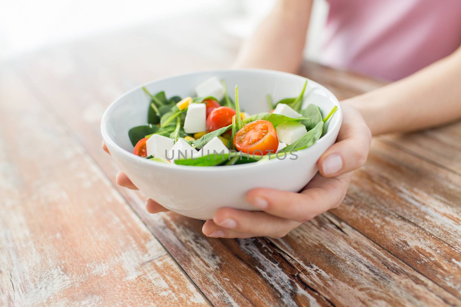 healthy eating, dieting and people concept - close up of young woman hands showing salad bowl at home