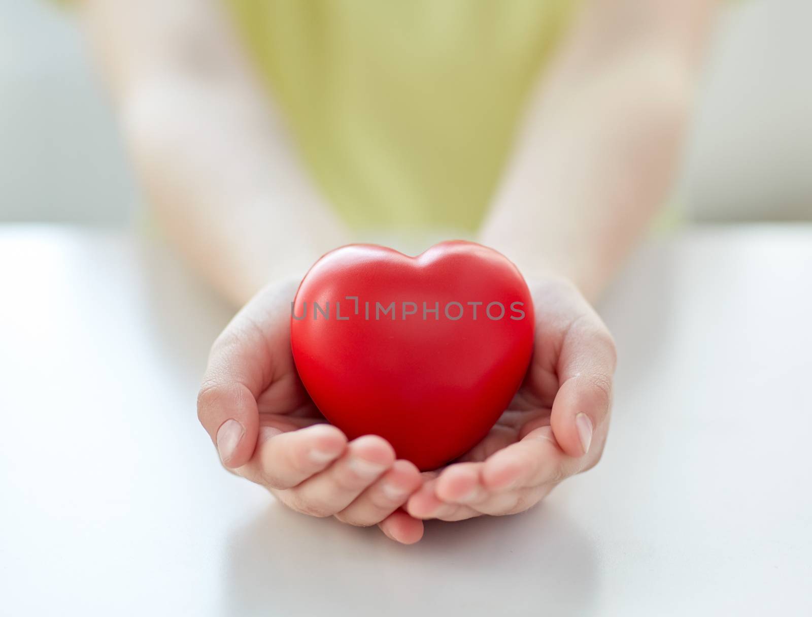 people, love, charity and family concept - close up of child hands holding red heart shape at home