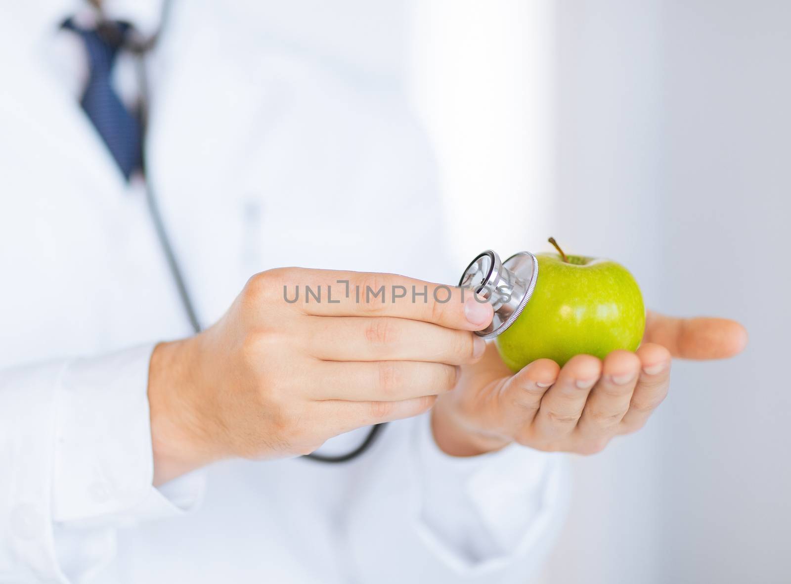 close up of male doctor with green apple and stethoscope