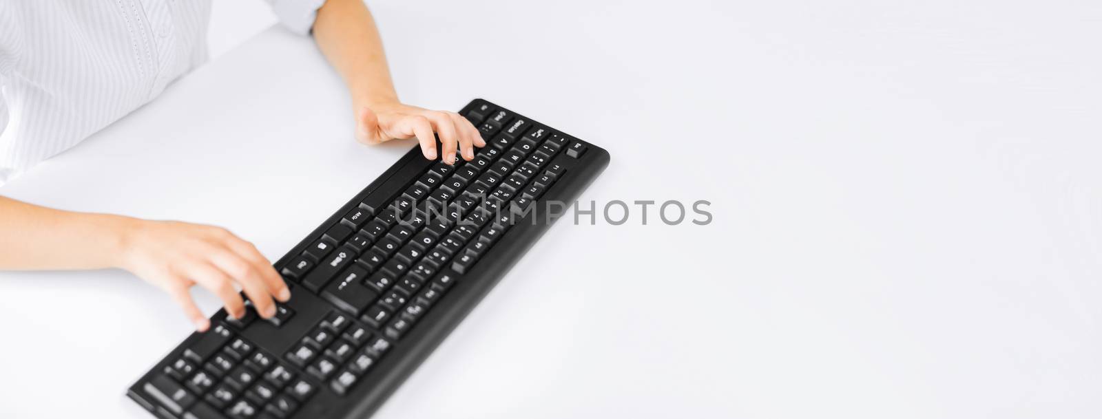 education, school and technology concept - little student girl hands typing on keyboard with copyspace