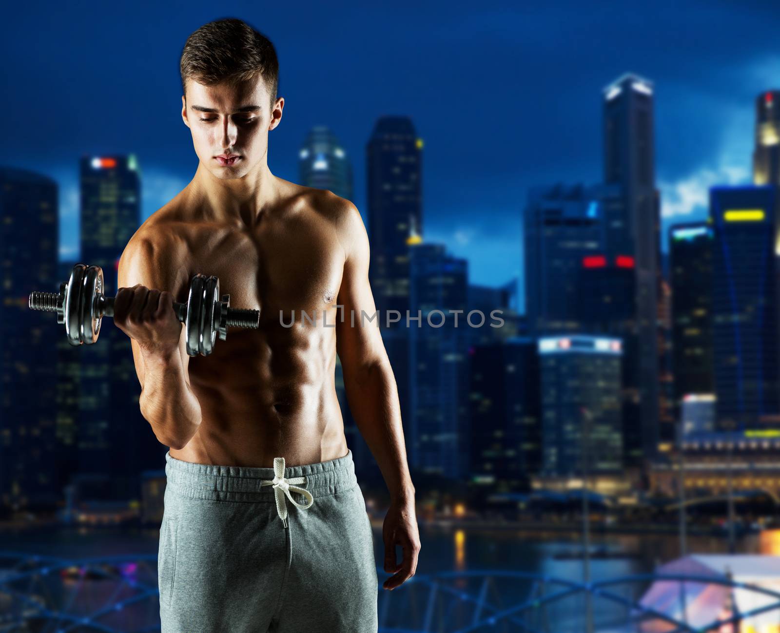 sport, fitness, weightlifting, bodybuilding and people concept - young man with dumbbell flexing biceps over night city background