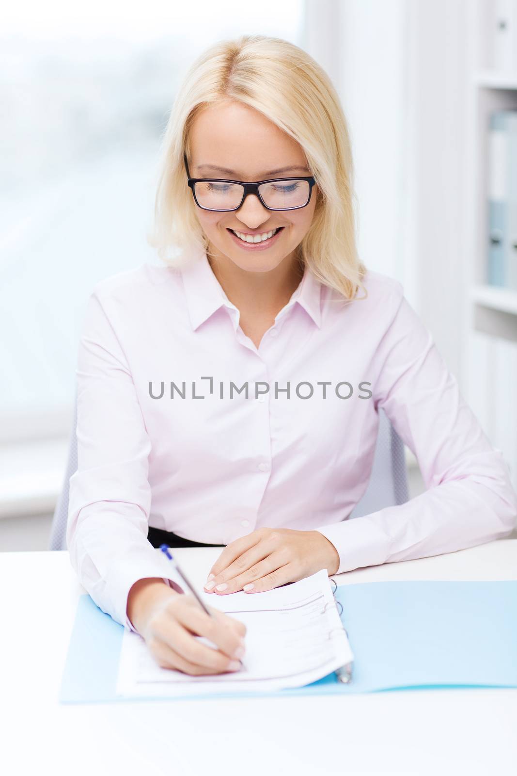 education, business and people concept - smiling businesswoman or student in eyeglasses with documents writing or making tax report in office