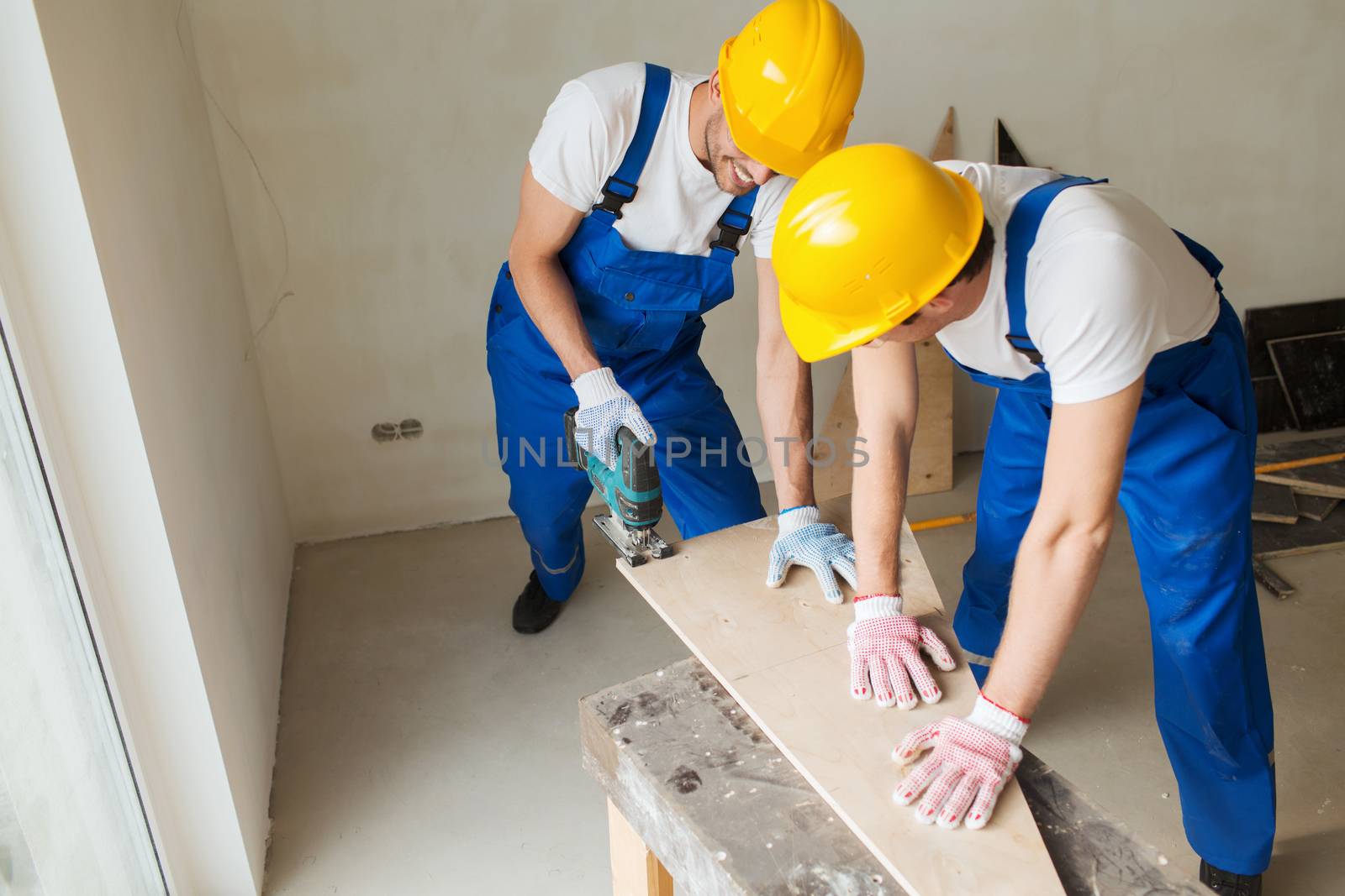 business, building, teamwork and people concept - group of smiling builders in hardhats with tools indoors