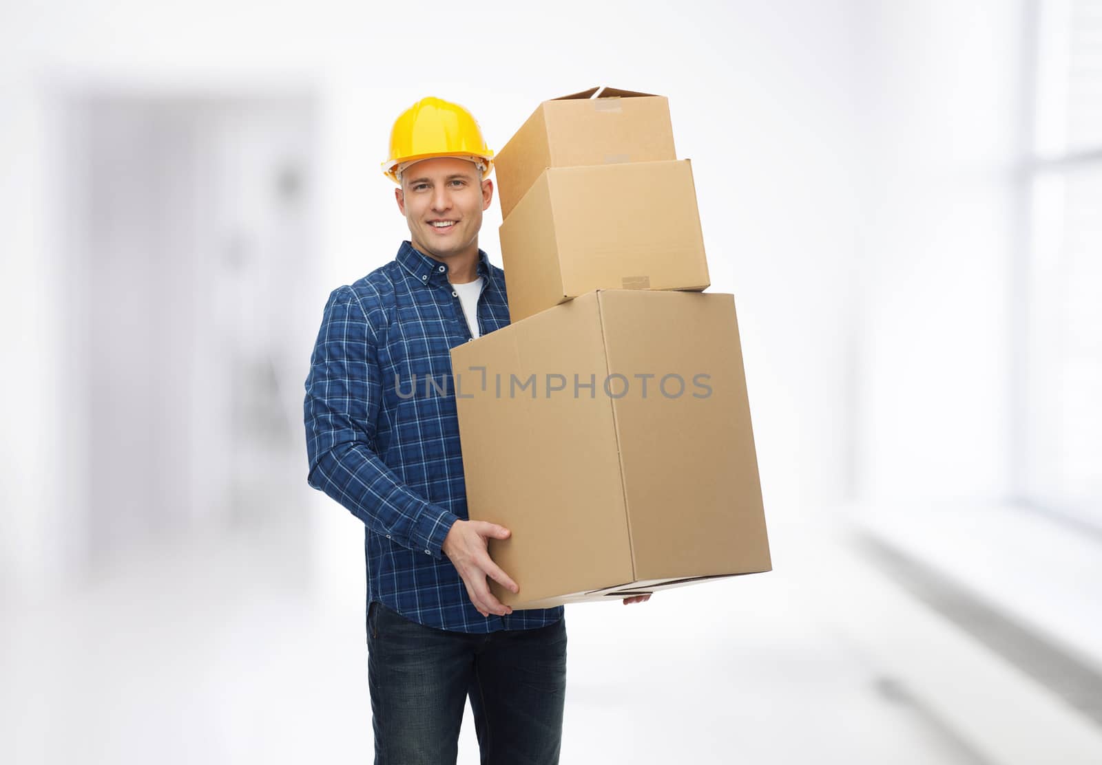 repair, building, construction, loading and delivery concept - smiling man or loader in helmet with cardboard boxes over room background