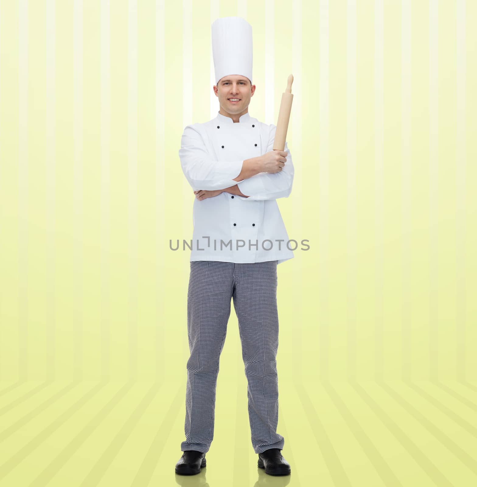 cooking, profession and people concept - happy male chef cook holding rolling pin over yellow background