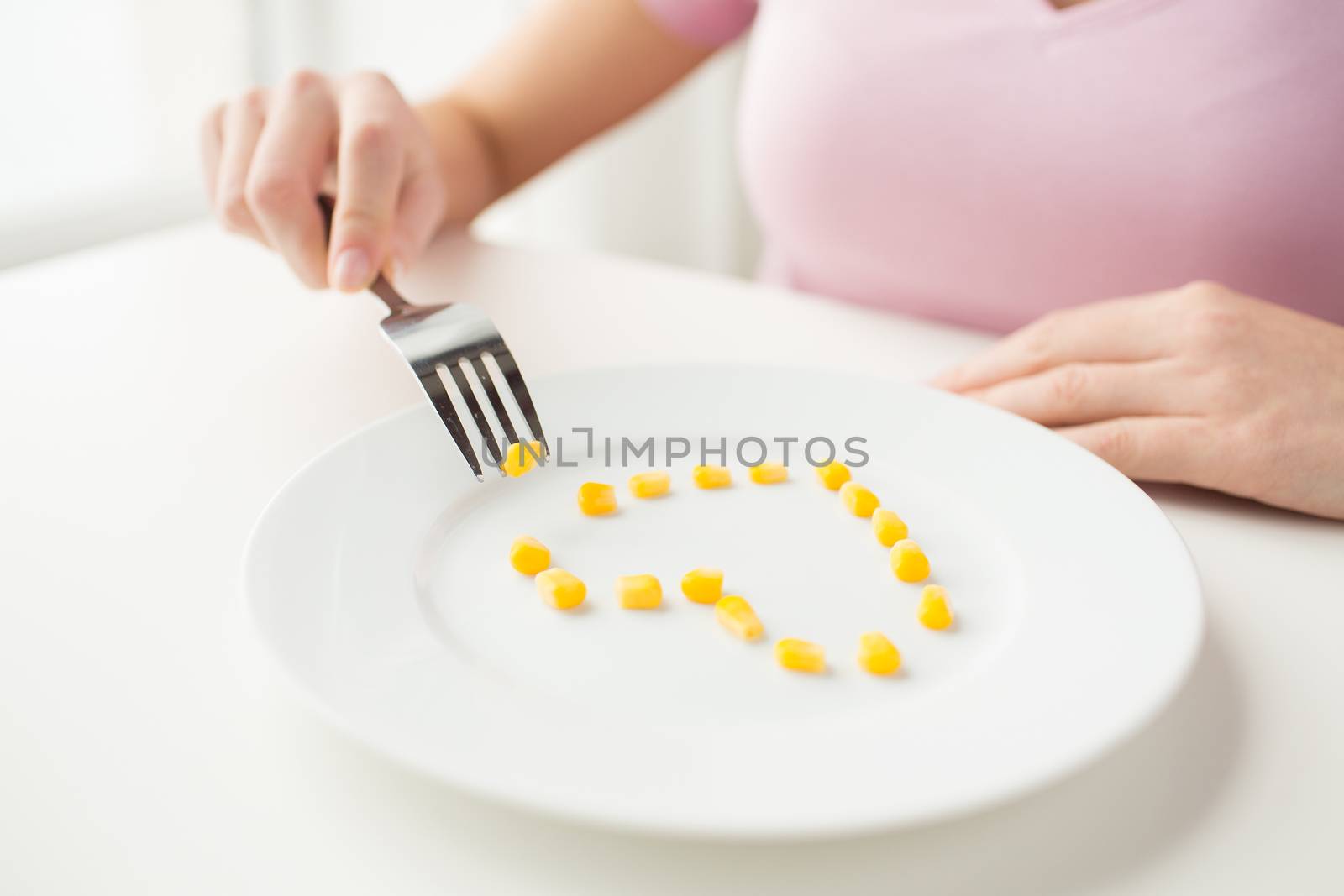 healthy eating, dieting, vegetarian food and people concept - close up of woman with fork eating corn in shape of heart