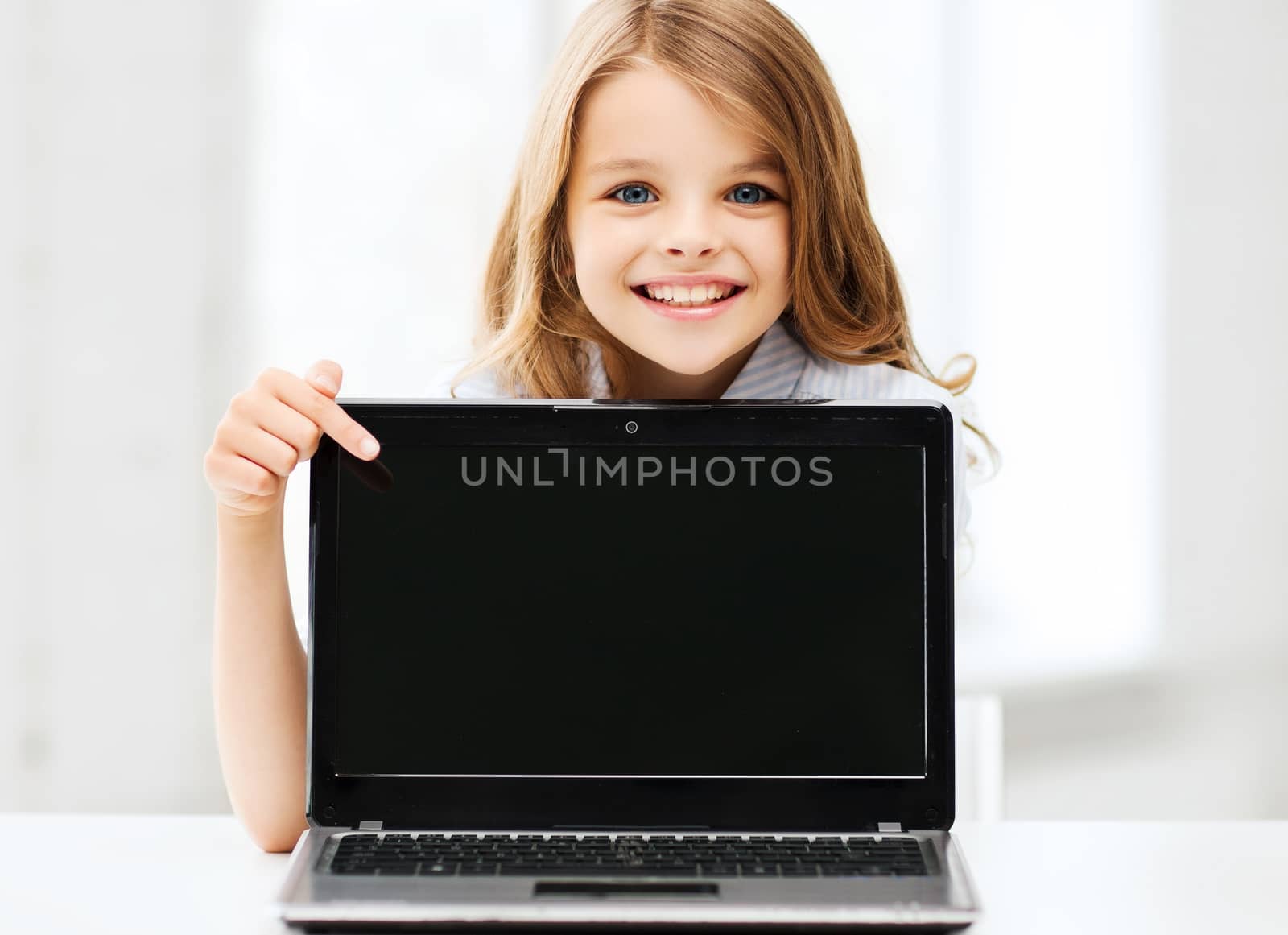 education, school, technology and internet concept - little student girl pointing at laptop pc at school