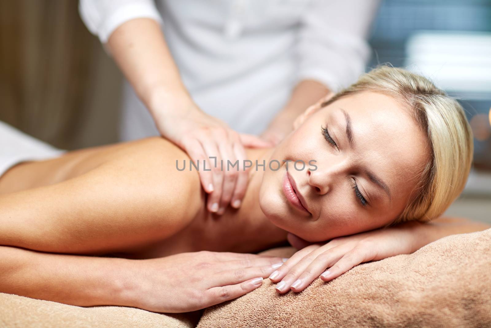 people, beauty, spa, healthy lifestyle and relaxation concept - close up of beautiful young woman lying with closed eyes and having hand massage in spa