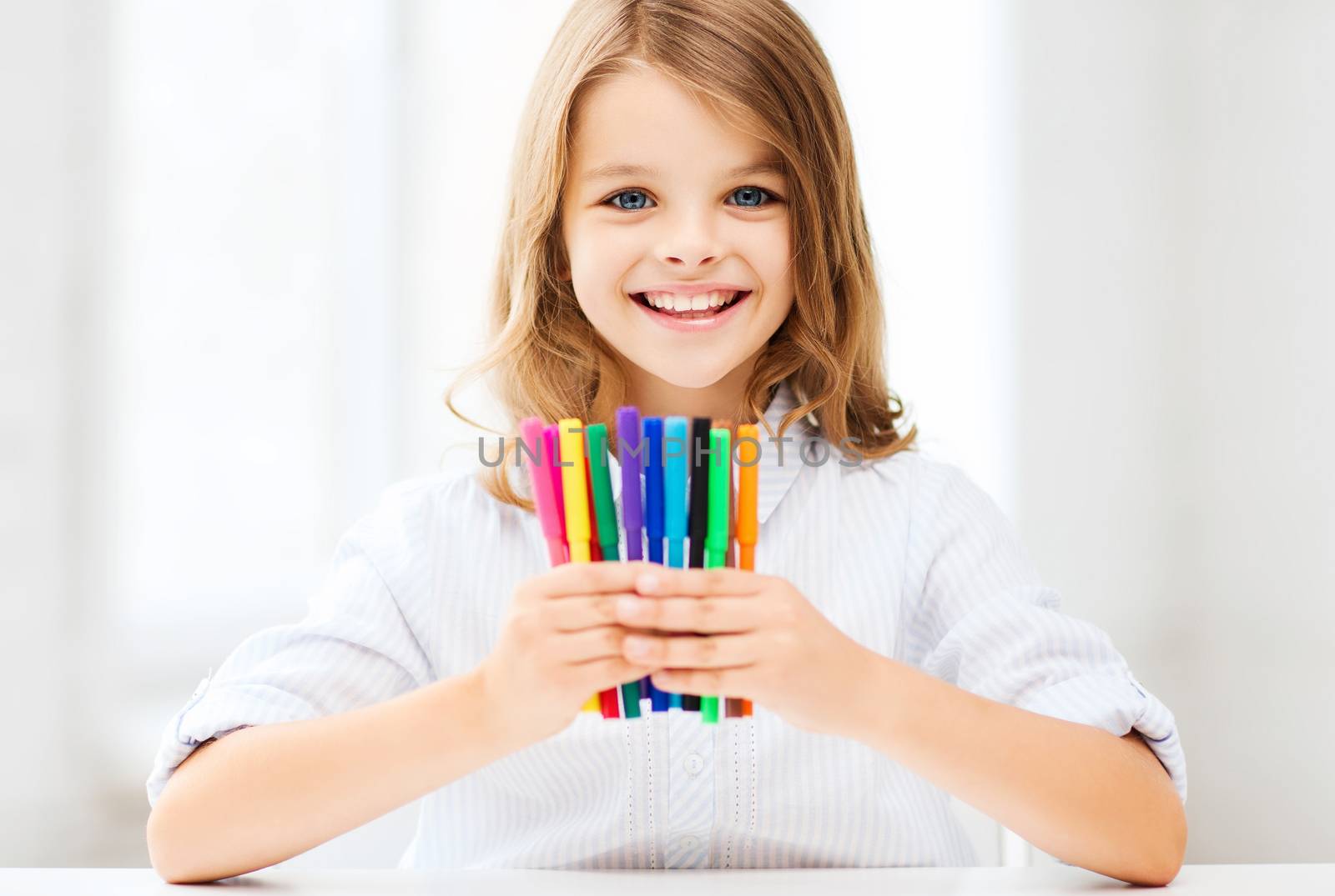 education and school concept - little student girl showing colorful felt-tip pens at school