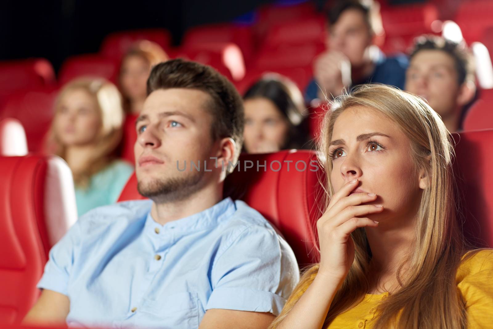 happy friends watching horror movie in theater by dolgachov