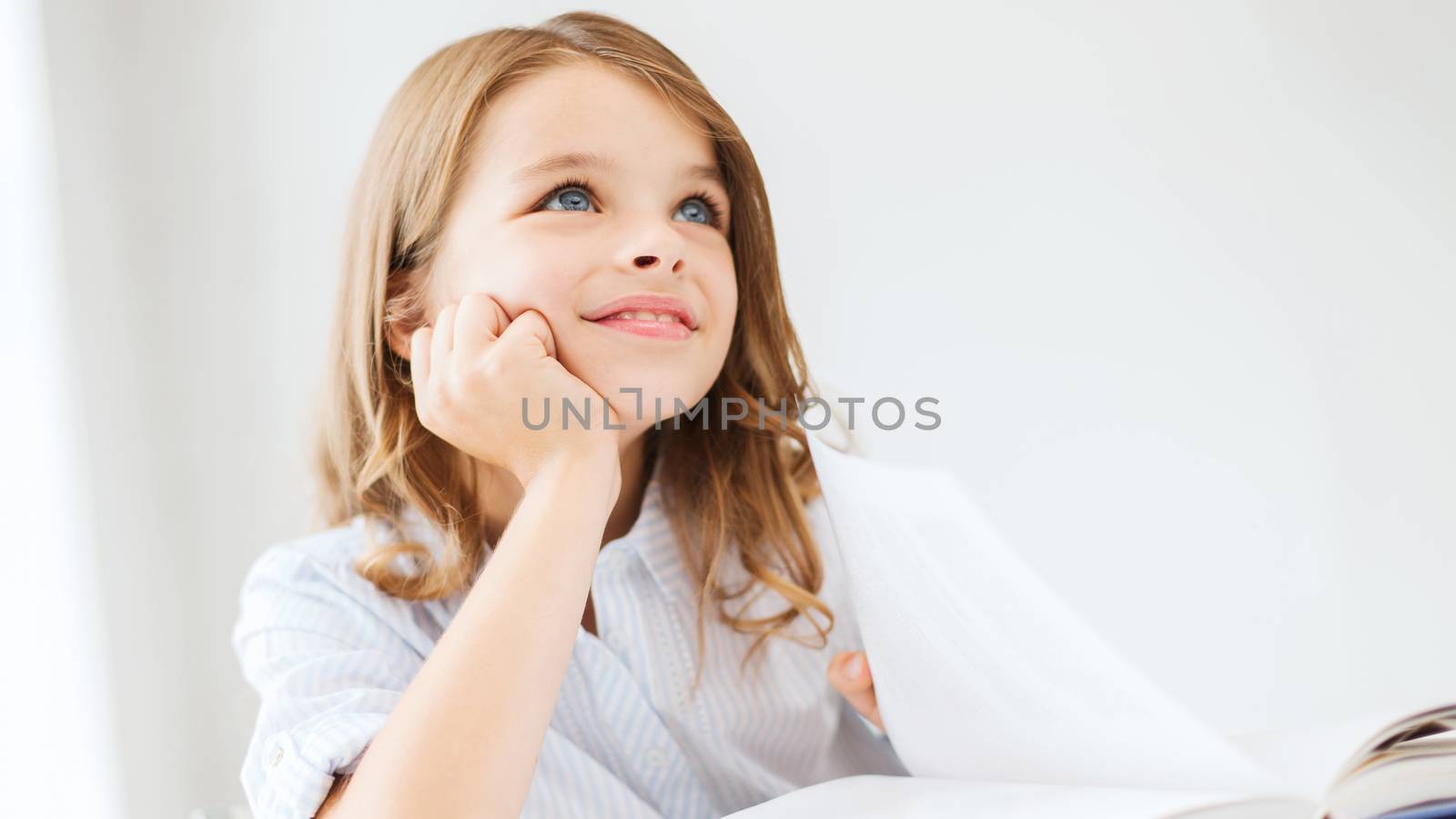 education and school concept - little student girl writing in notebook at school