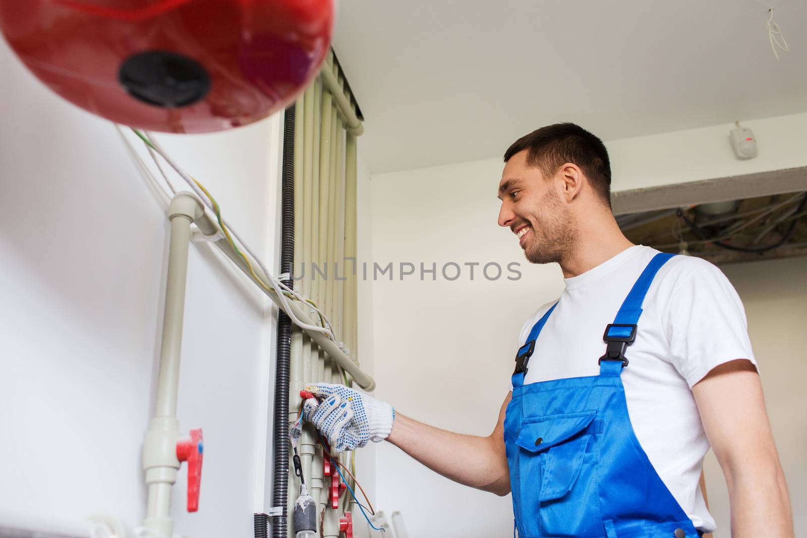 building, profession and people concept - builder or plumber working with water pipes in boiler room