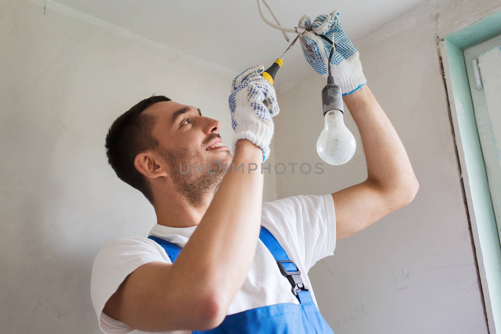 building, renovation, technology, electricity and people concept - builder with screwdriver fixing socket indoors