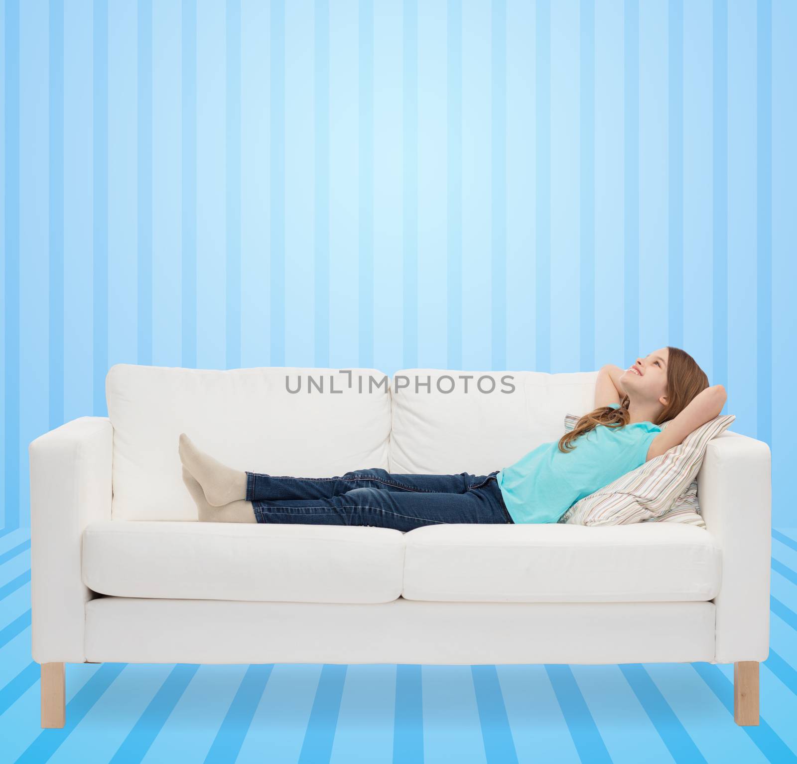 home, leisure, people and happiness concept - smiling little girl lying on sofa and dreaming over blue striped background