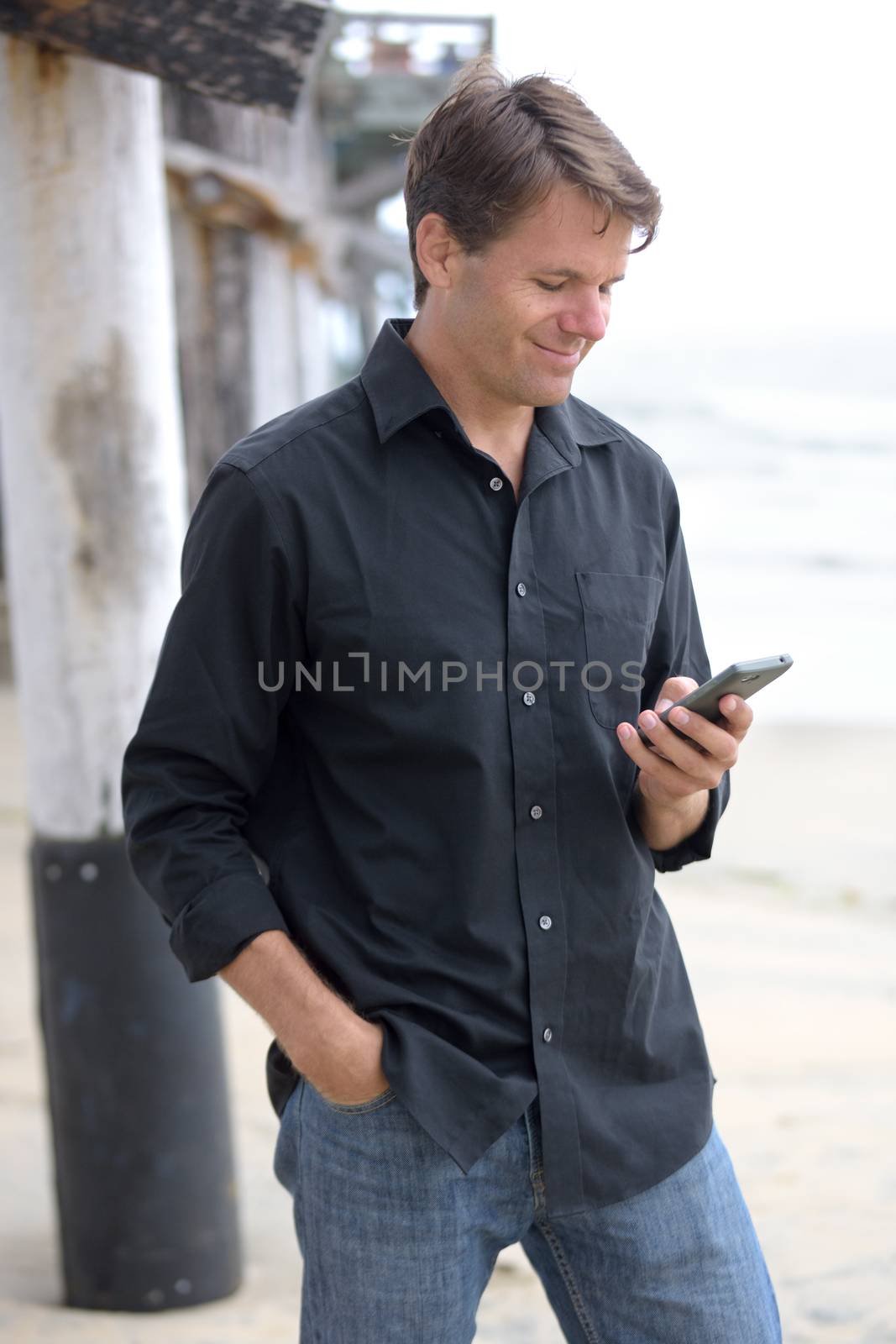 Man communicating with smart phone at beach by shakzu