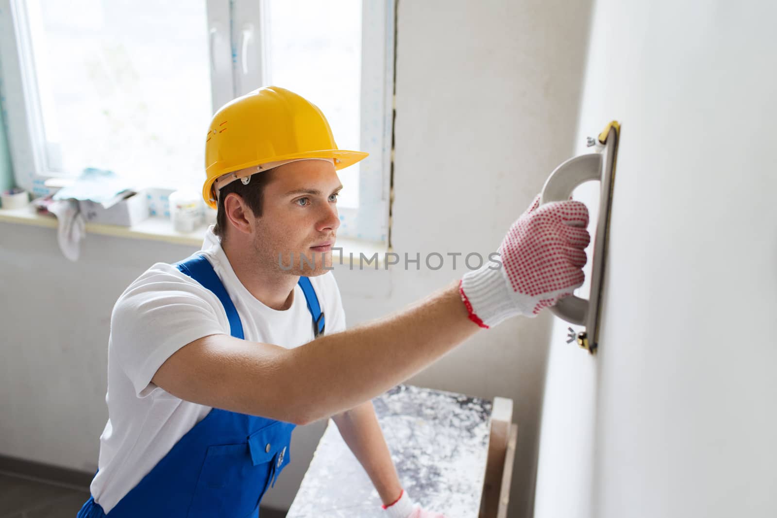 smiling builder with grinding tool indoors by dolgachov