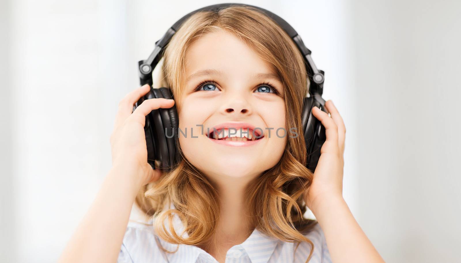 home, technology and music concept - little girl with headphones at home