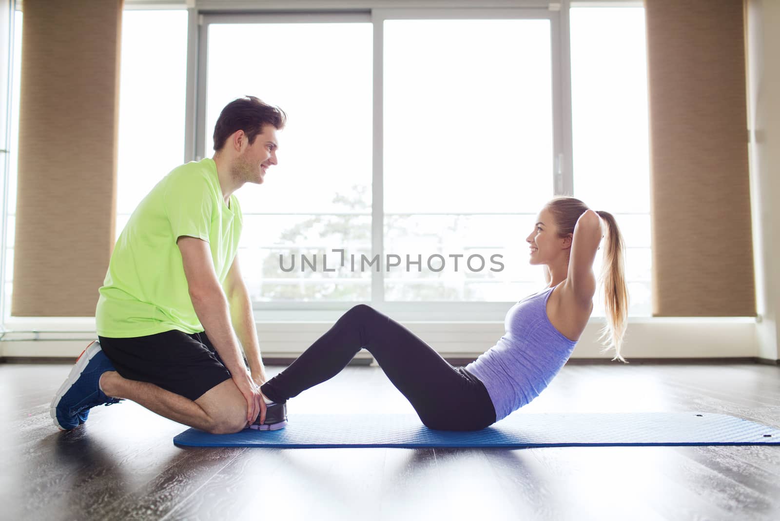 fitness, sport, training, teamwork and people concept - woman with personal trainer doing sit ups in gym