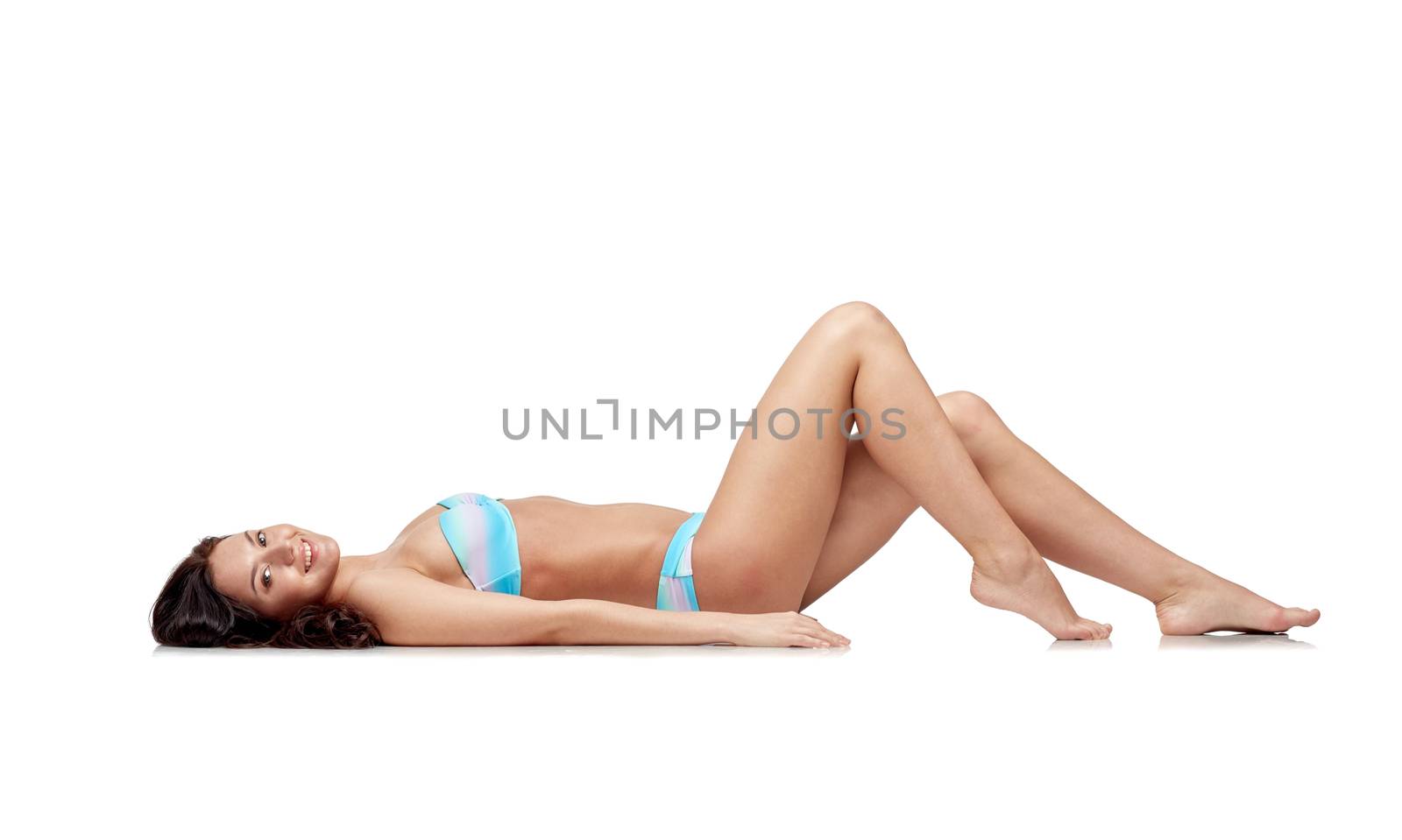 people, fashion, swimwear, summer and beach concept - happy young woman lying in bikini swimsuit