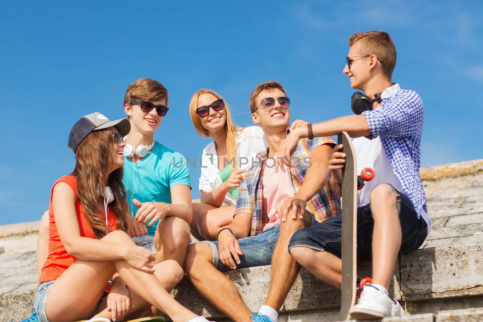 group of smiling friends sitting on city street by dolgachov