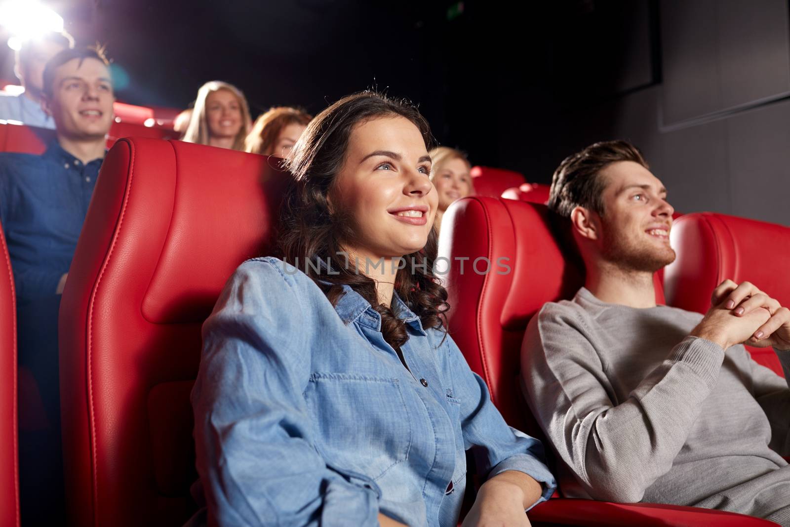 cinema, entertainment and people concept - happy friends watching comedy movie in theater