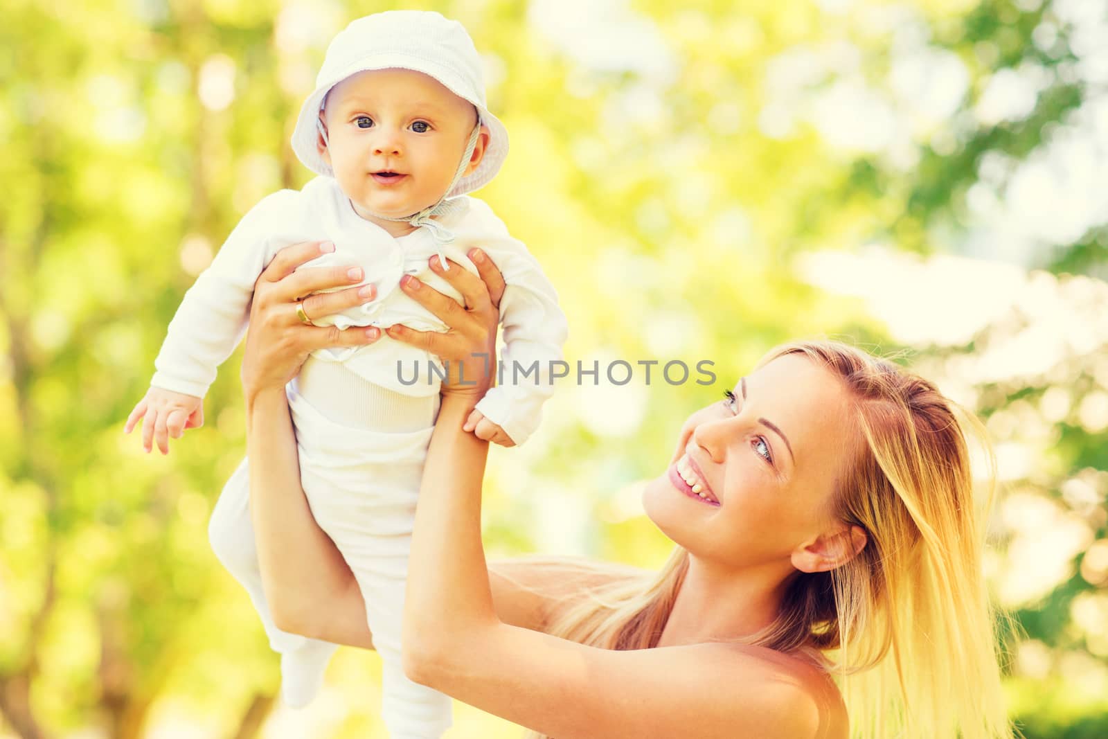 family, child and parenthood concept - happy mother holding and raising little baby up in park
