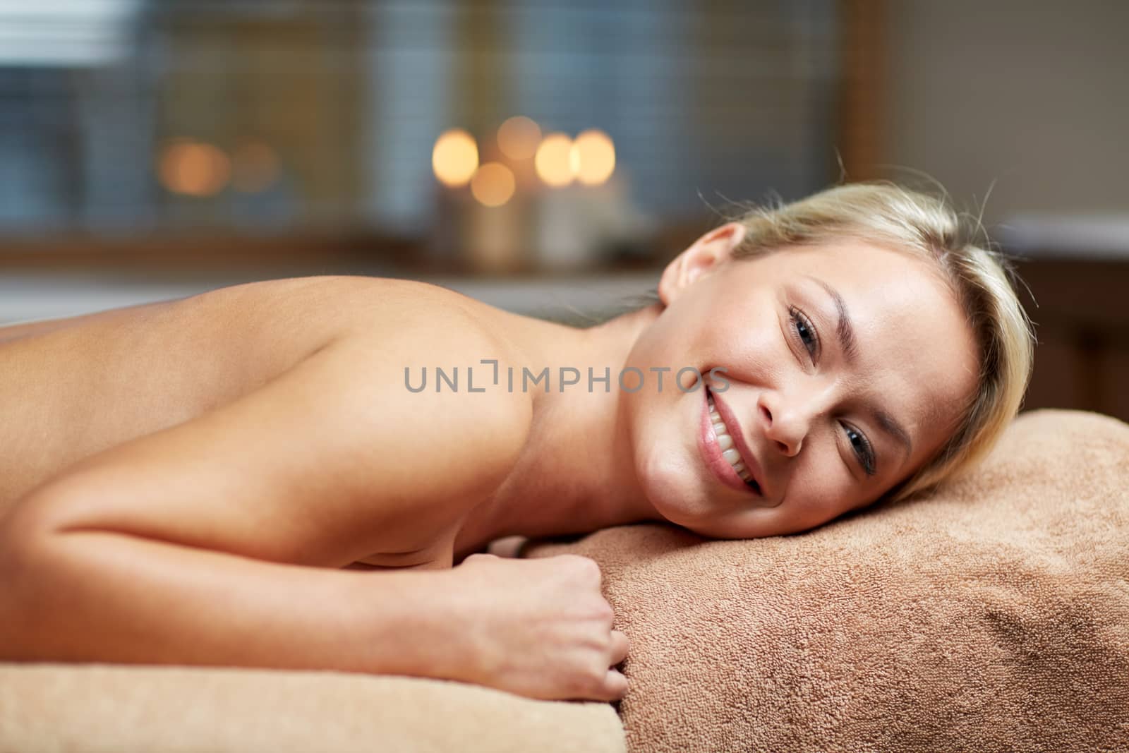 people, beauty, spa, healthy lifestyle and relaxation concept - beautiful young woman lying on massage table in spa