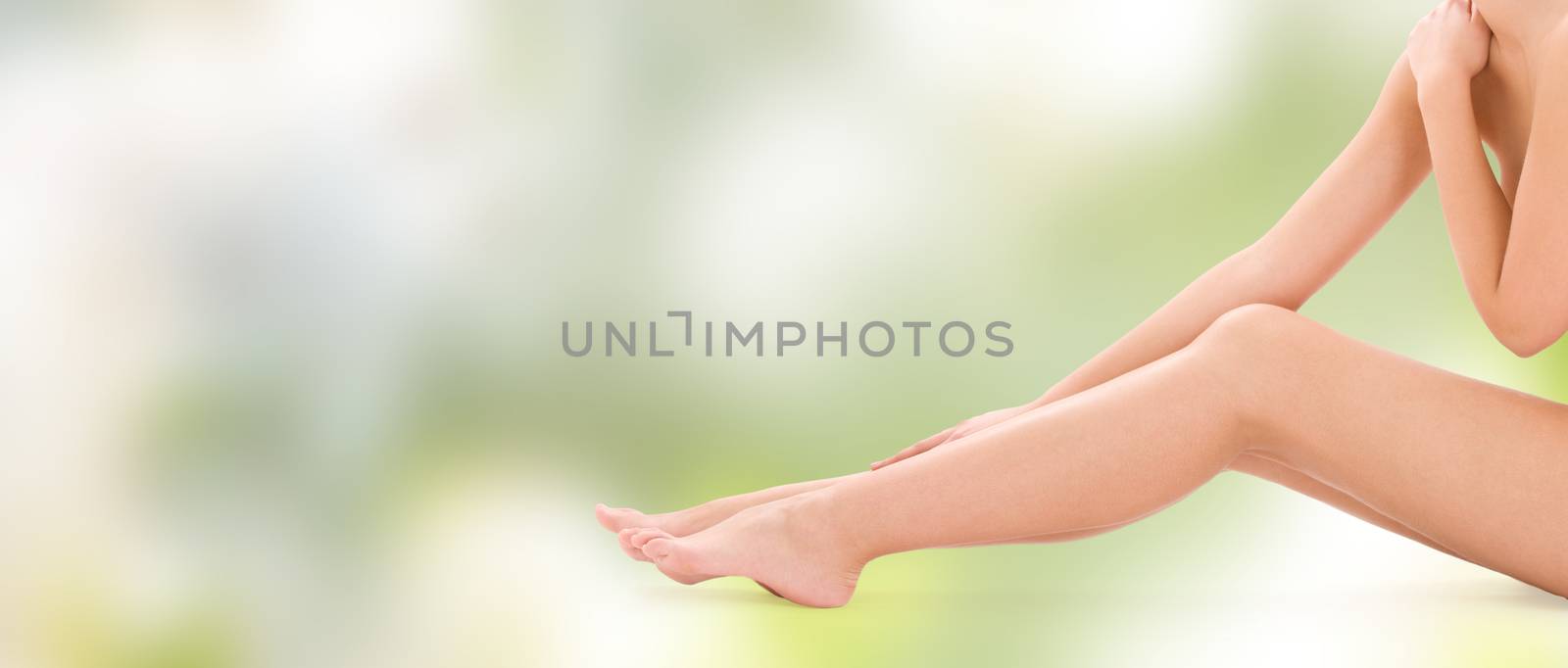 people, beauty, health and body care concept - close up of naked woman legs over green background