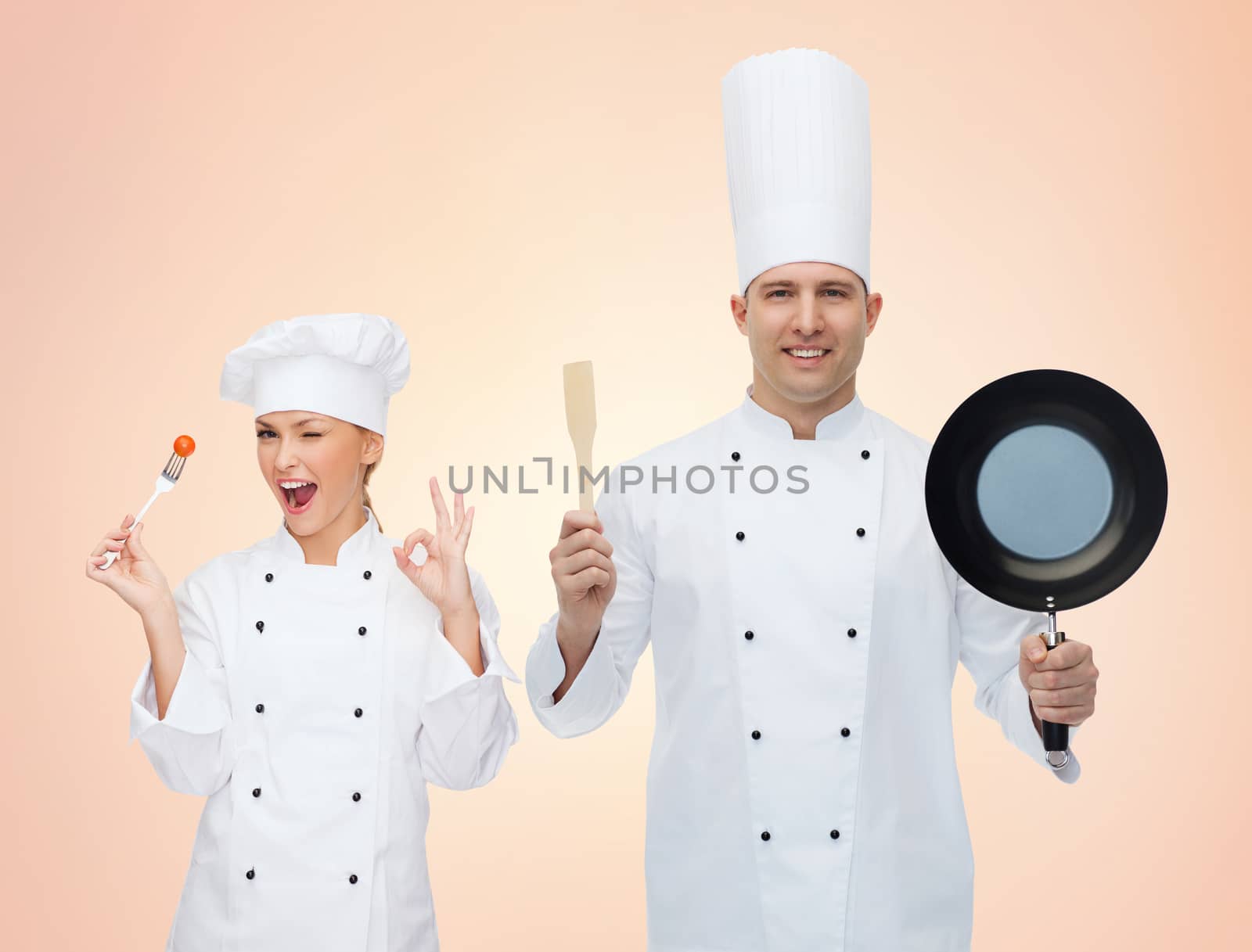 cooking, profession, teamwork, and people concept - happy chefs or cooks couple with kitchenware over beige background