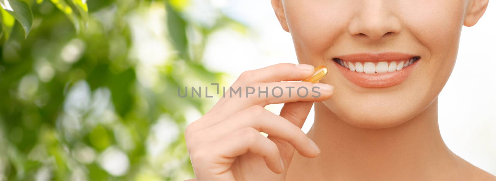 beautiful woman holding omega 3 vitamins capsule by dolgachov