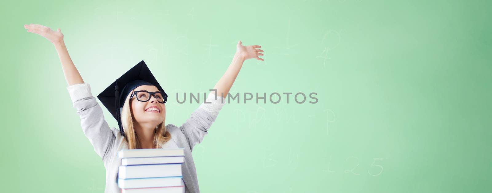 education, happiness, graduation and people concept - picture of happy student in mortar board cap with stack of books over green background