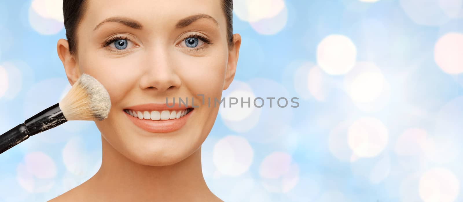 happy woman applying powder foundation with brush by dolgachov