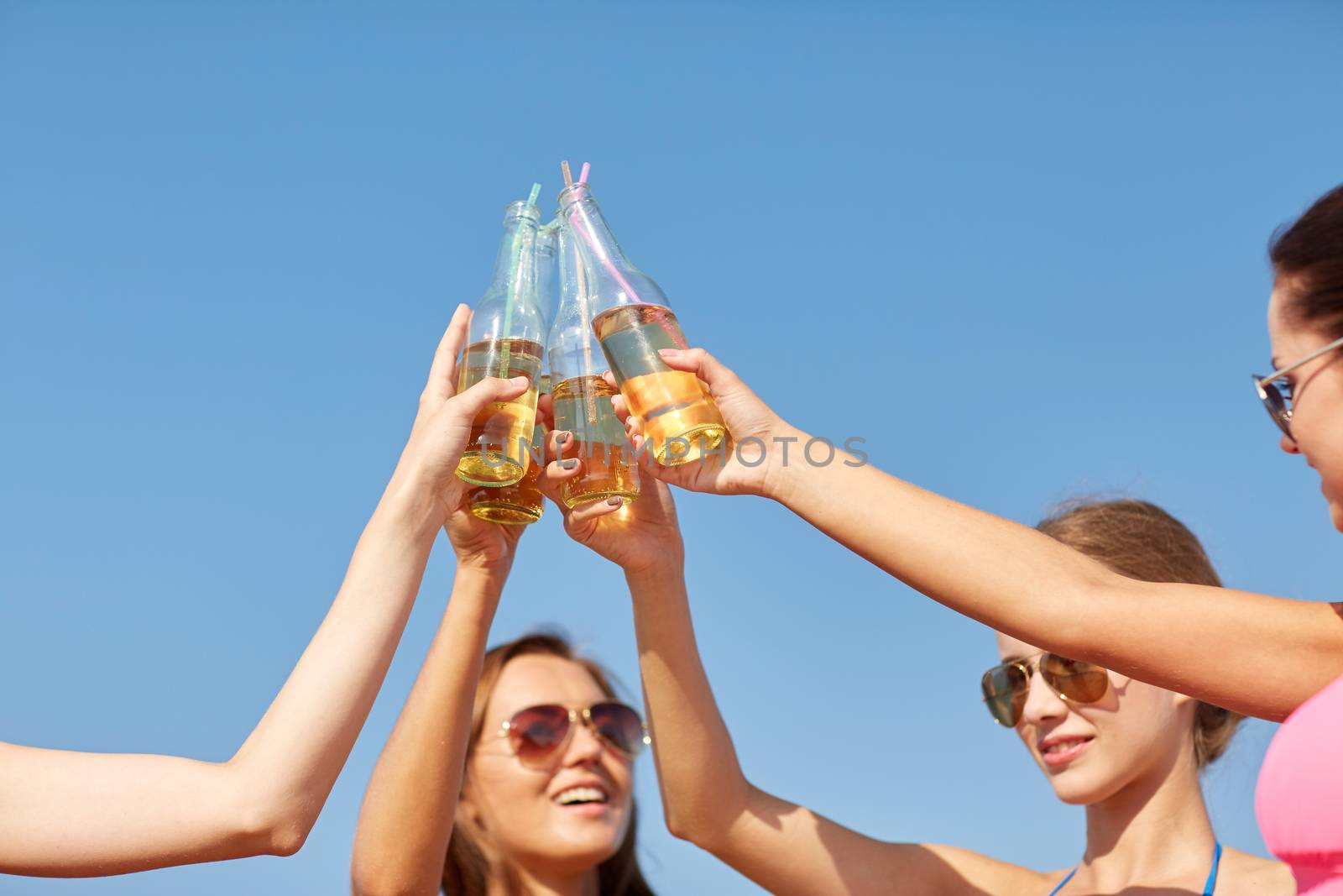 summer vacation, holidays, party, travel and people concept - close up of happy young women with drinks clinking bottles