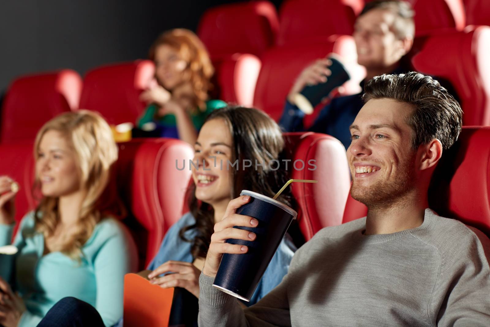 happy friends watching movie in theater by dolgachov