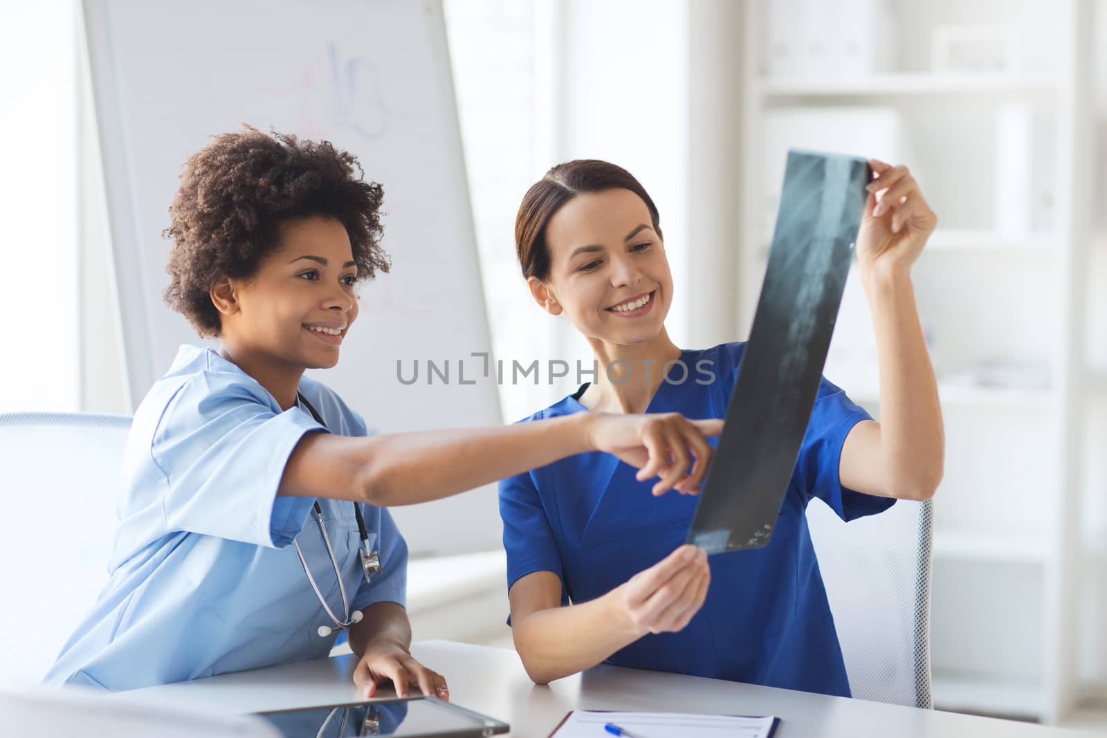 happy female doctors with x-ray image at hospital by dolgachov