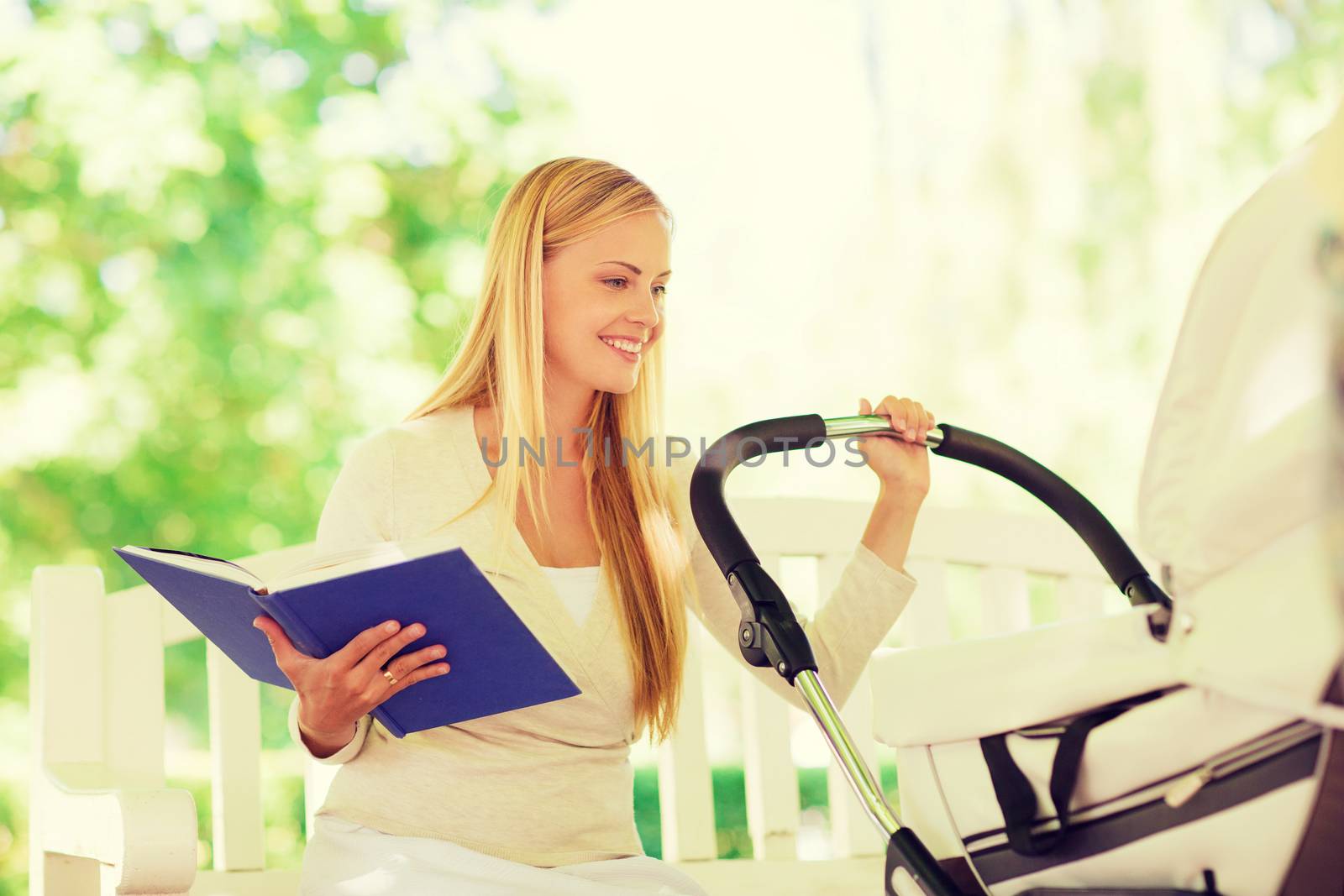 family, child, leisure, education and parenthood concept - happy mother with baby stroller reading book in park